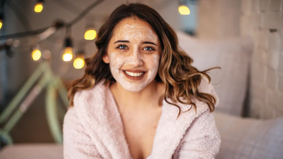 Junge Frau mit Gesichtsmaske macht Beauty-Tag zu Hause