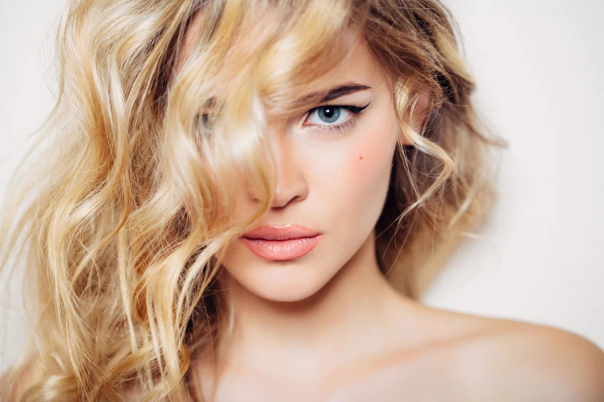 Eine Frau mit voluminösem Haar , eine Strähne fällt ihr ins Gesicht