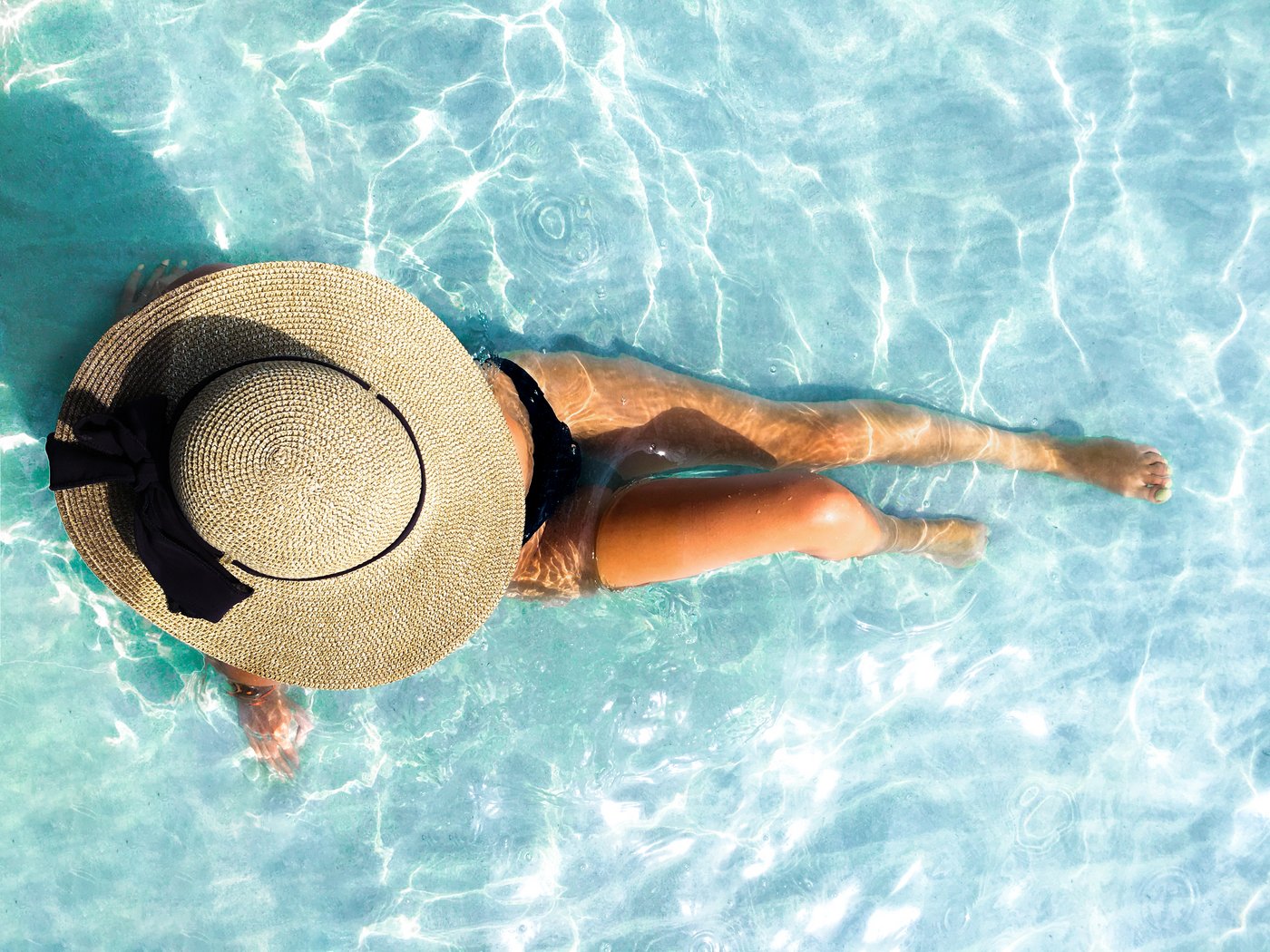Junge Frau mit Sonnenhut sonnt sich im Pool