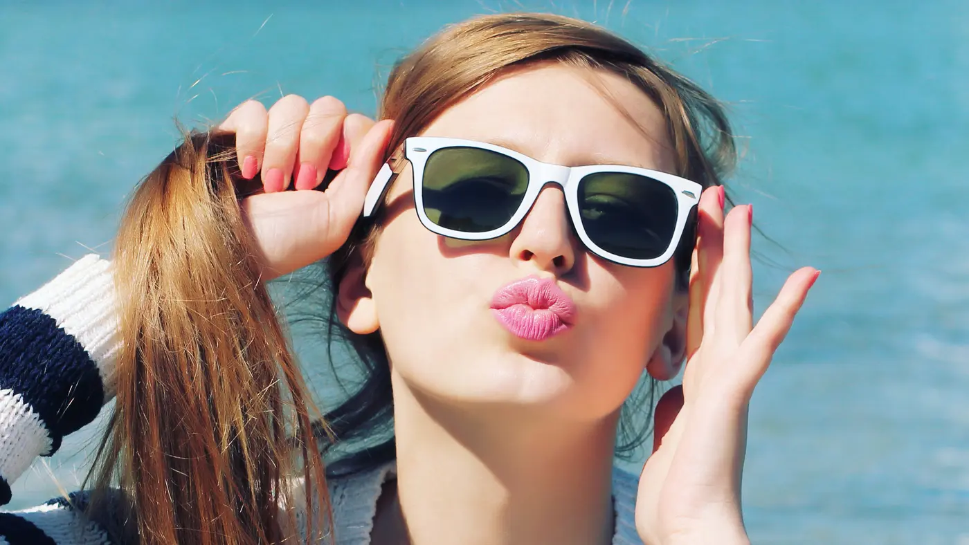 Junge Frau mit Sonnenbrille macht einen Kussmund