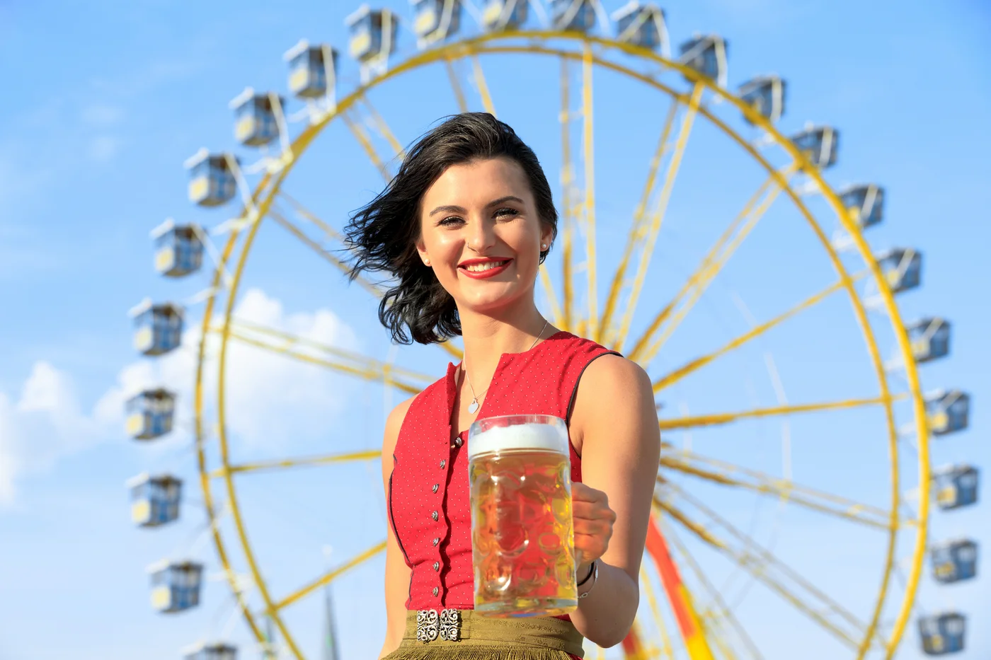 Frau im Dirndl vor dem Riesenrad mit Bierkrug