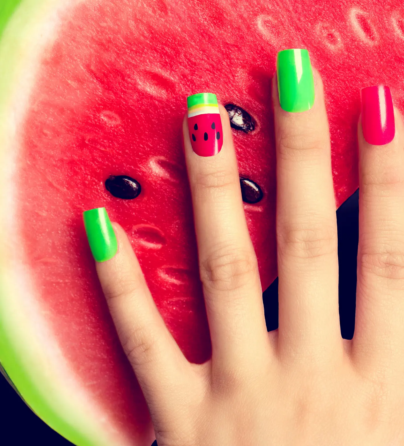 Hand mit bunt lackierten Fingernägel liegt auf einer Wassermelone