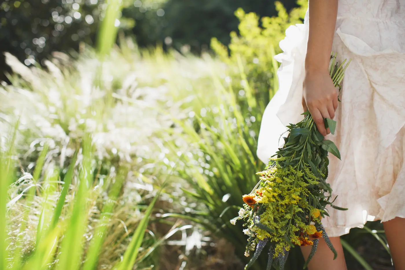 Eine Frau die einen Blumenstrauss in der Hand hält und auf einer Wiese steht