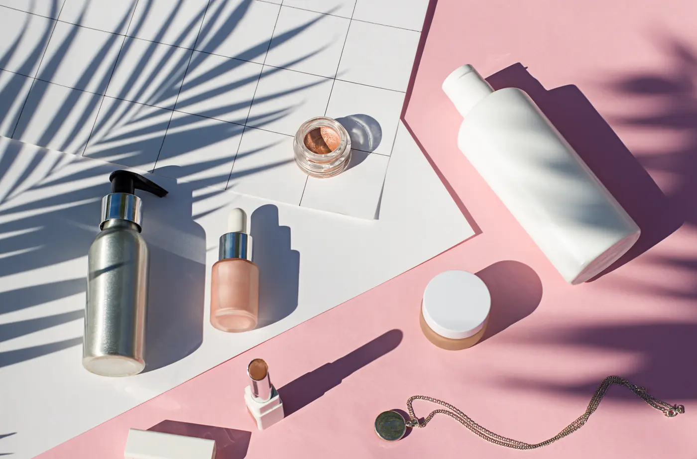 Sommerliche Beautyprodukte auf rosa Hintergrund