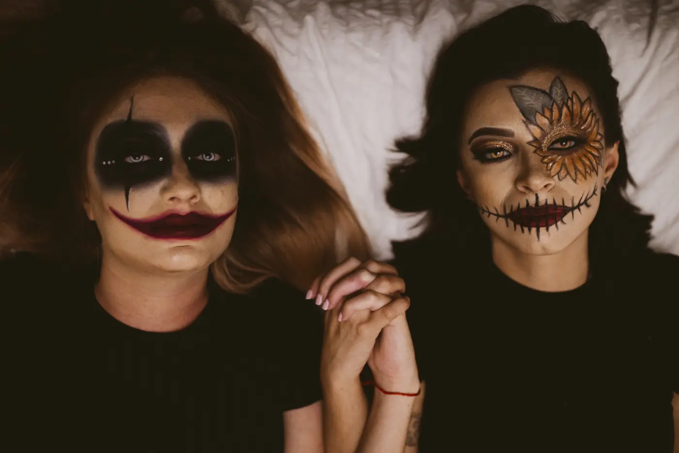 Zwei Freundinnen mit gruseligem Halloween Make-up halten Hände