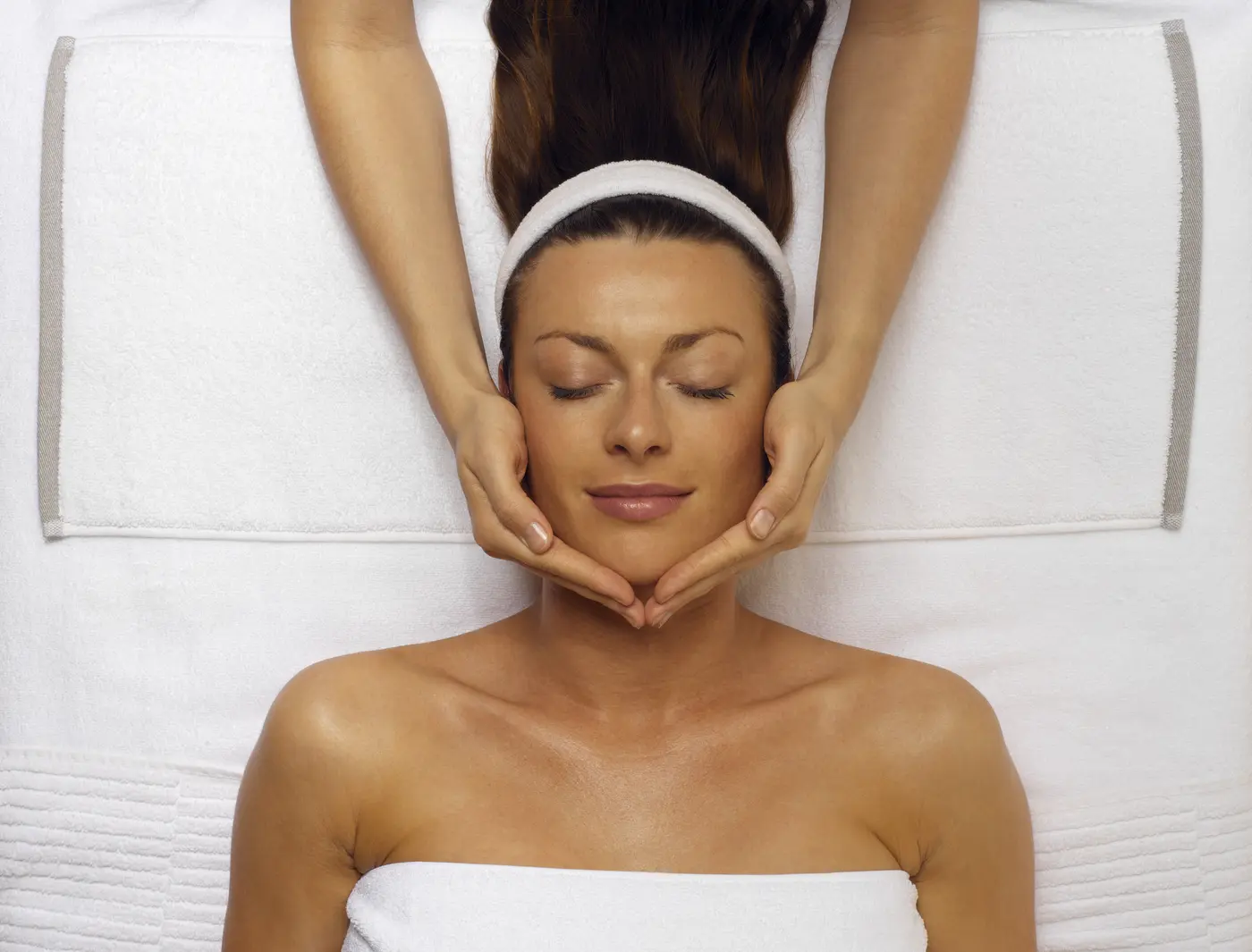 Junge Frau bekommt einer Gesichtsmassage in der Beauty Lounge
