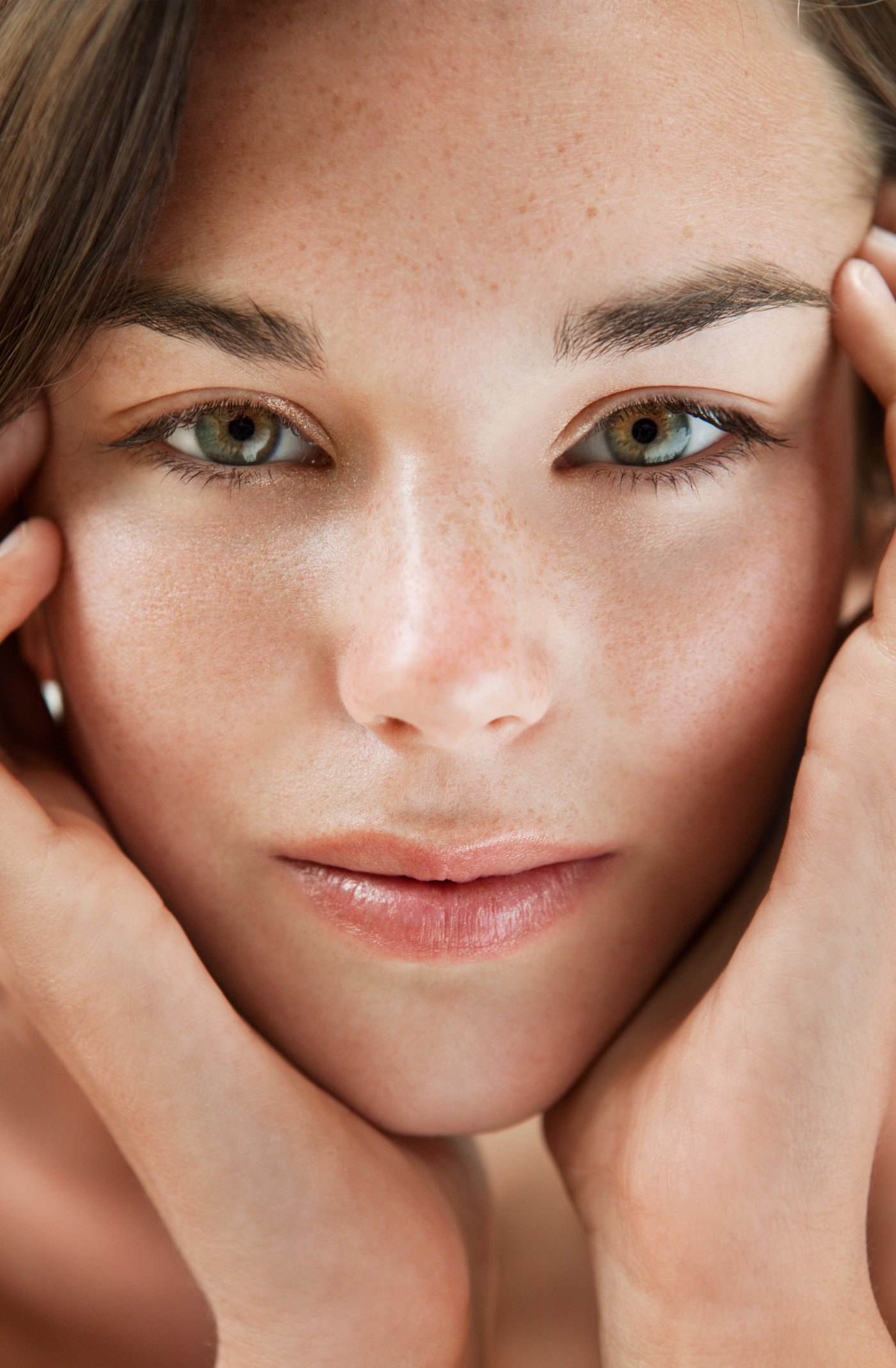 Model in Nahaufnahme hält ihr ungeschminktes Gesicht