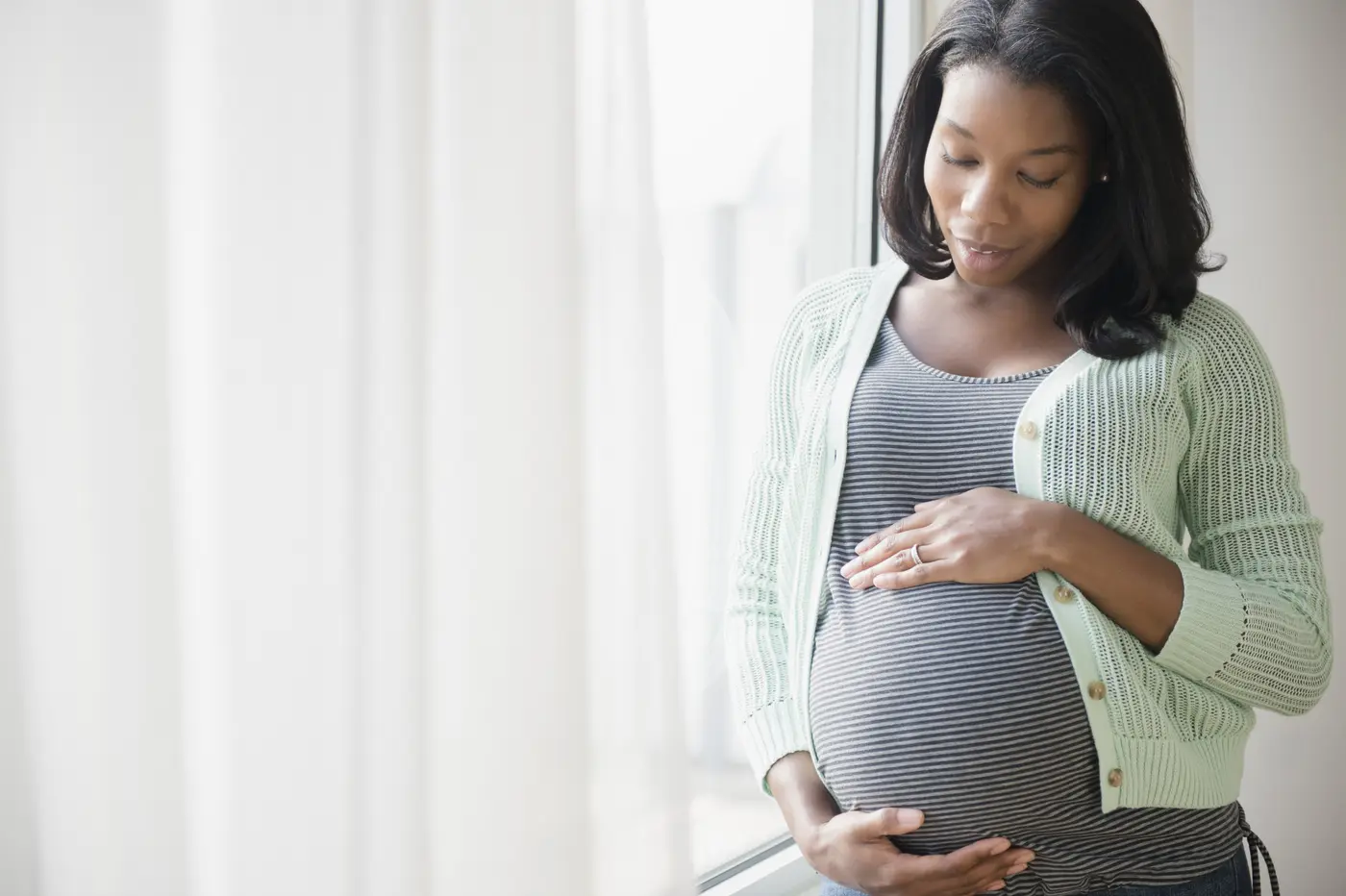 Afroamerikanische Frau hält ihren Babybauch