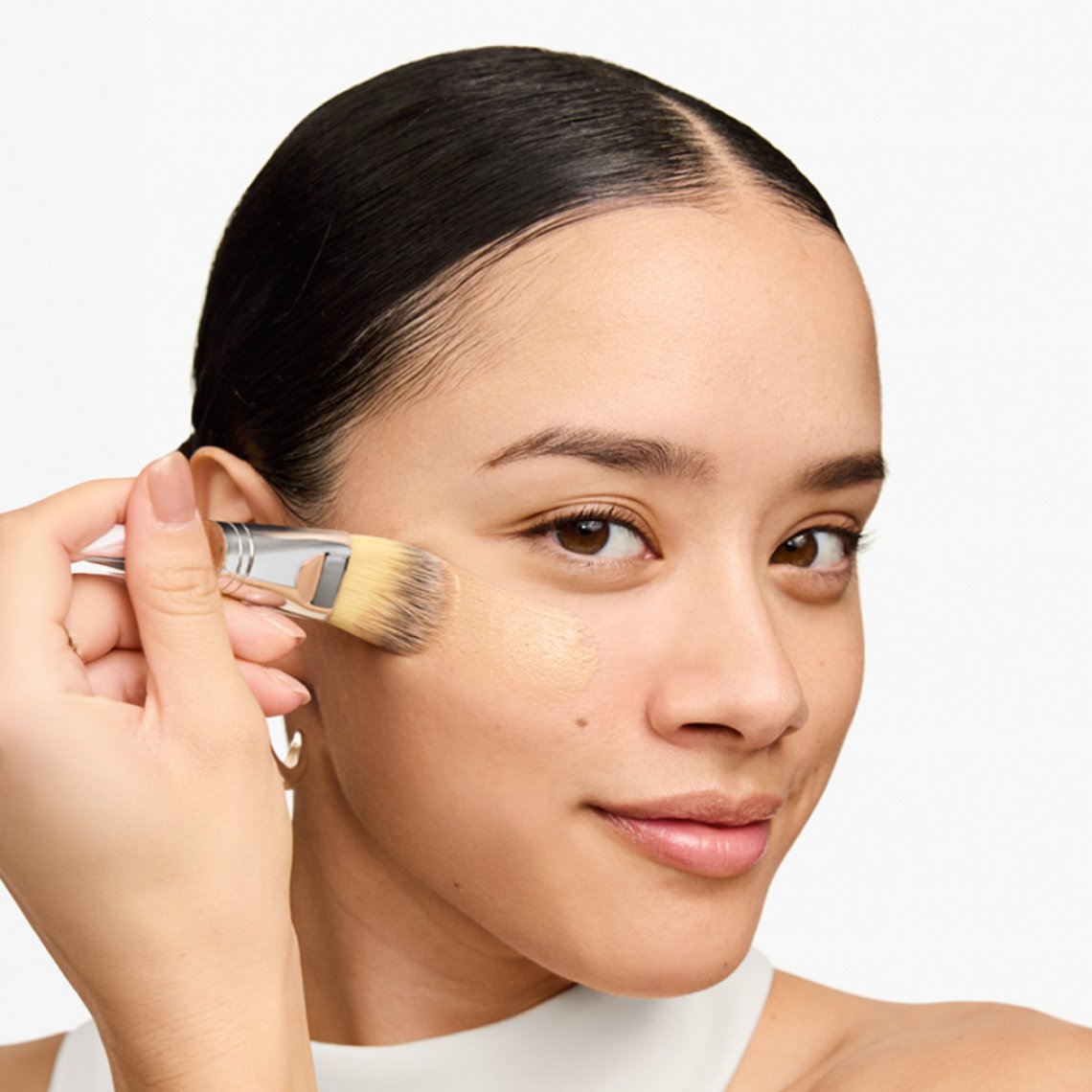 Frau trägt Clinique Even Better Foundation mit Kabuki-Pinsel auf die Wange auf, heller Hautton
