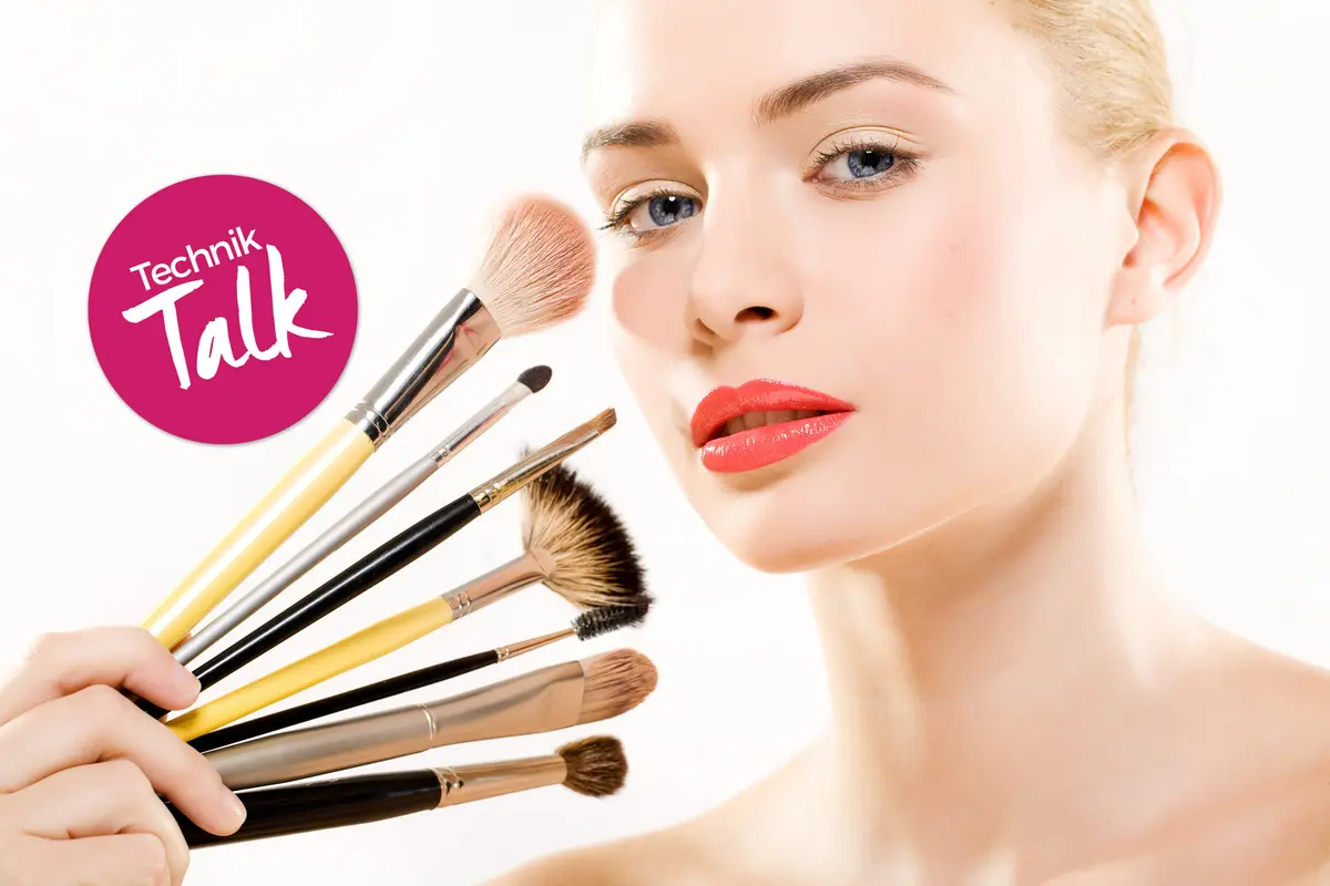 Blonde Frau mit diversen Make-up-Pinseln im Gesicht