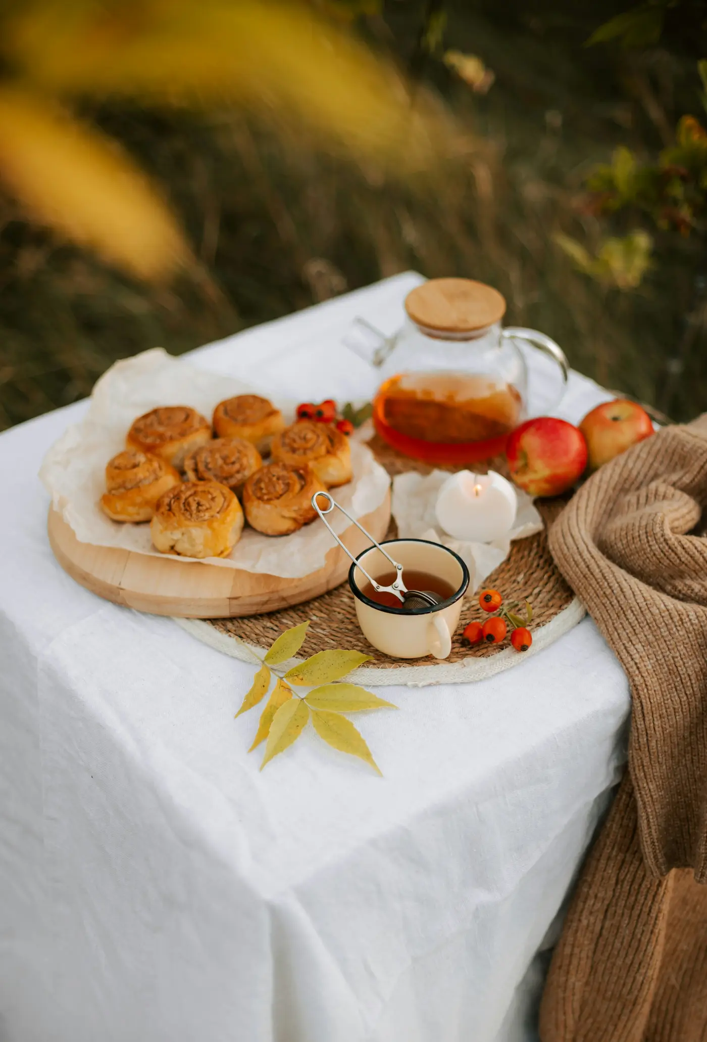 Tisch mit Zimtschnecken und einer Teekanne im Herbst