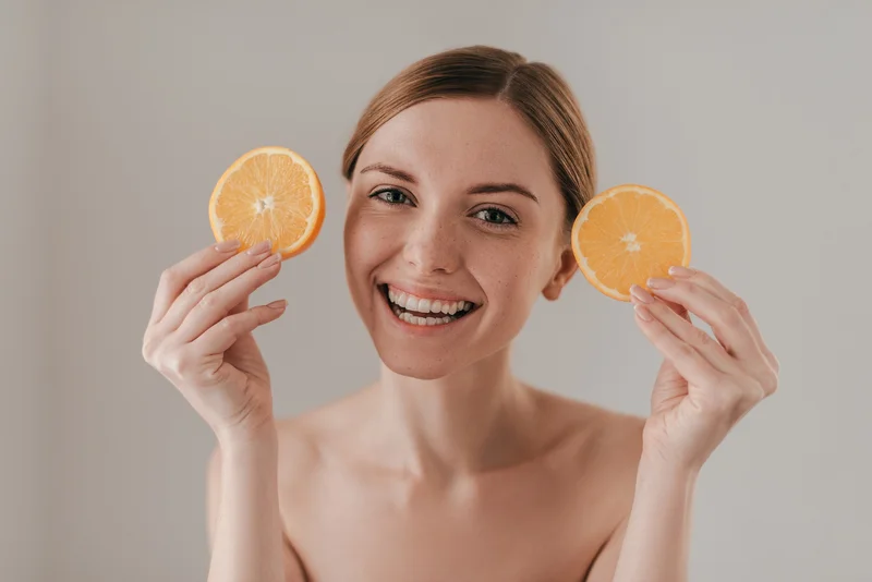 Frau mit Orangenscheiben in der Hand