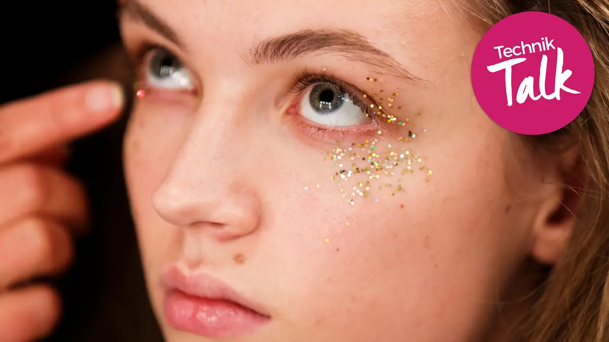 Eine Frau bekommt Glitter auf die Wangenknochen geschminkt