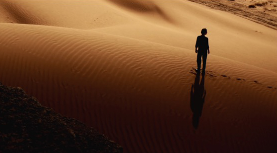 Mann läuft durch die Wüste bei Sonnenuntergang