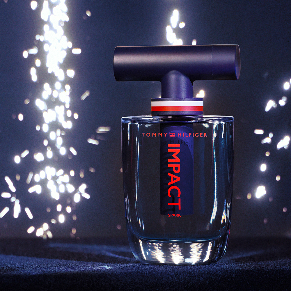 Tommy Hilfiger Impact Spark Eau de Toilette Flakon Impact Spark von Tommy Hilfiger und im Hintergrund Funken
