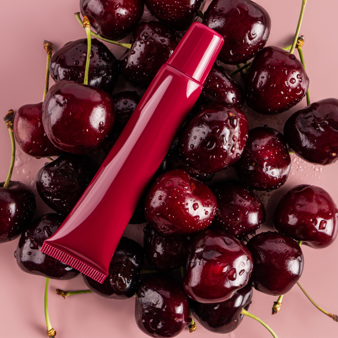 Rote Lipgloss-Verpackung auf vielen Kirschen
