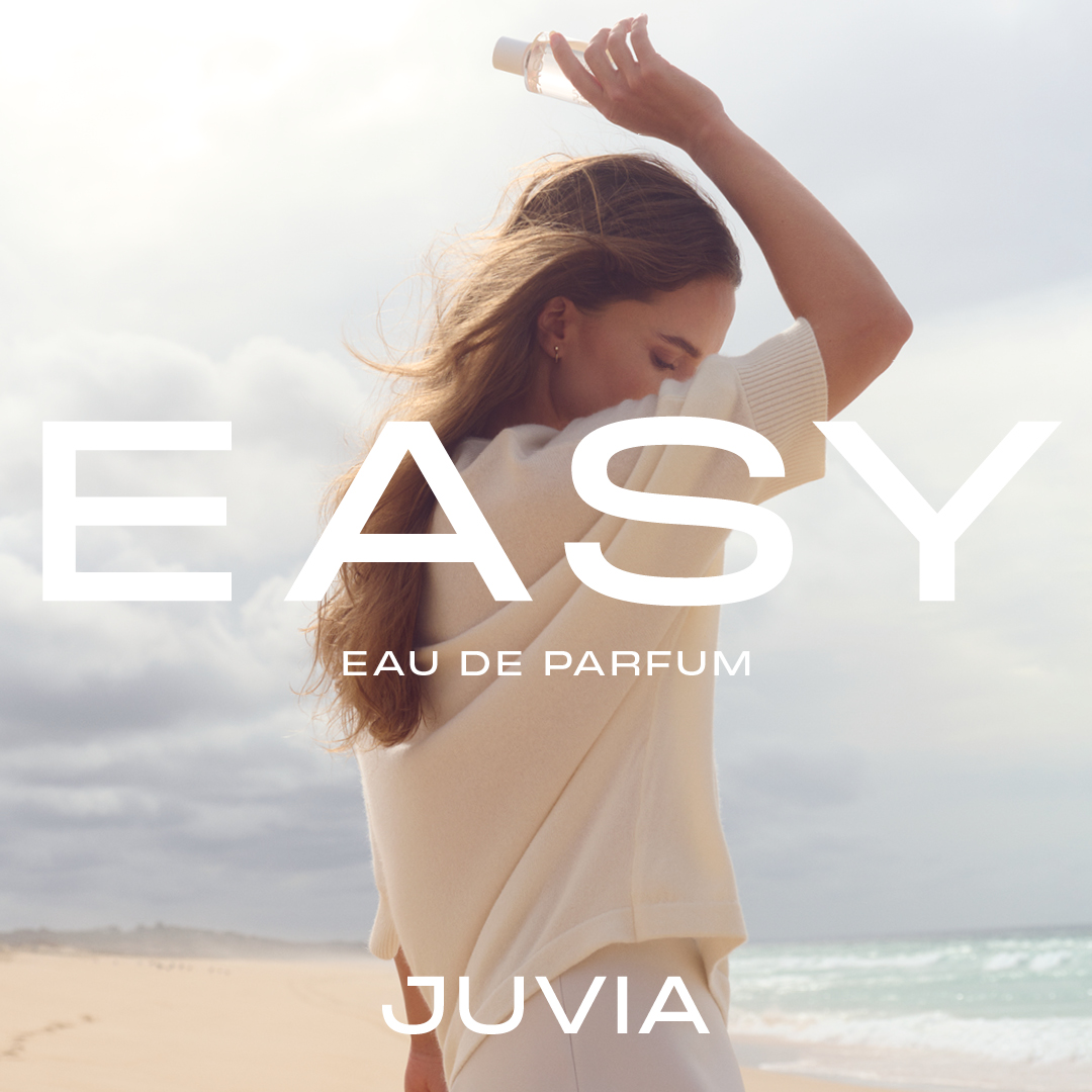 Junge Frau in Loungewear hält einen Parfumflakon hoch