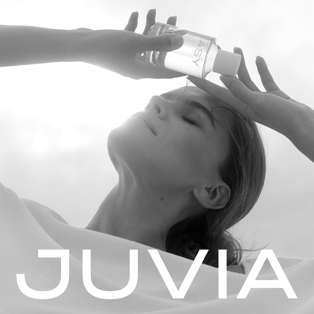 Junge Frau mit geschlossenen Augen hält sich einen Parfumflakon an die Stirn