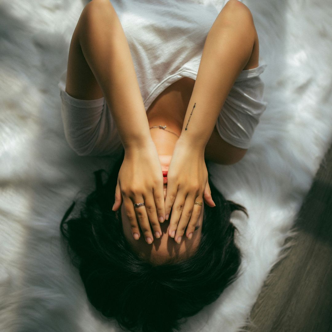 Frau verdeckt ihr Gesicht mit den Händen – Stress und hormonelle Schwankungen können Pickel begünstigen. Frau verdeckt ihr Gesicht mit den Händen – Stress und hormonelle Schwankungen können Pickel begünstigen.